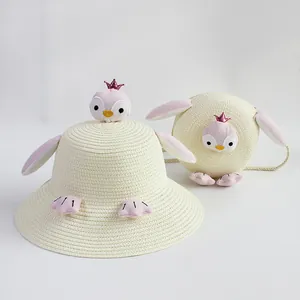 Detalle de sombrero de paja para niños y bolso de pingüino crema con corona pequeña