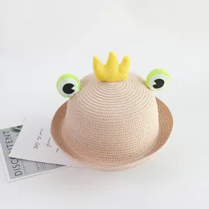 Close-up of kids straw sun hat featuring a cartoon frog design and plush crown detail