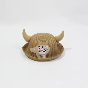 Détail d'un chapeau de paille pour enfant avec cornes jaunes et écusson de vache
