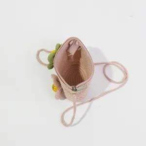 Detail of pink straw crossbody bag for kids featuring a zipper closure and floral decor