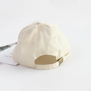 Back view of beige cotton kids baseball cap with adjustable brass buckle and vent holes