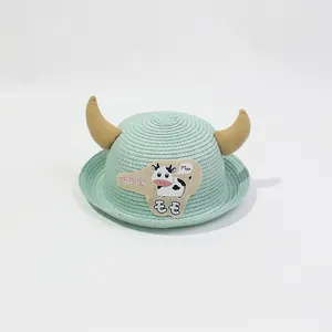 Détail d'un chapeau de paille vert clair pour enfants avec cornes de taureau 3D et décor de vache