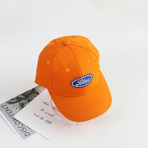Detail of vibrant orange cotton kids' baseball cap with blue embroidered patch logo