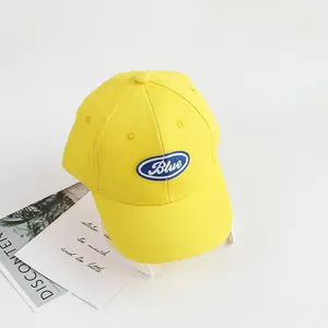 Detail of a bright yellow cotton baseball cap with blue embroidered letter badge