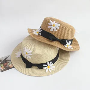 Chapeaux de paille plats beiges avec ruban noir et décorations de marguerites blanches