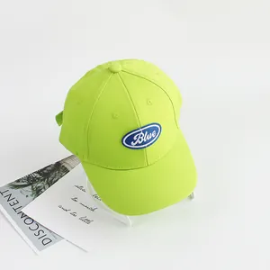 Detail of neon green cotton baseball cap with blue embroidery and curved brim for kids