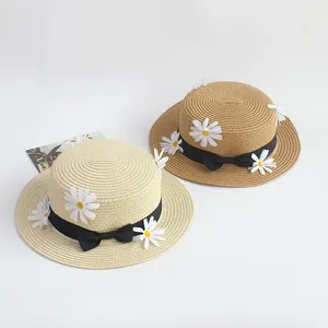 Détails de chapeaux de paille à sommet plat avec ruban noir et petites marguerites
