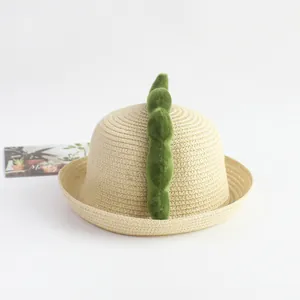 Detalle de sombrero de paja para niños con lindas puntas de dinosaurio de felpa
