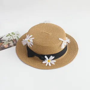 Détail du chapeau de paille avec ruban noir et fleurs de marguerites blanches