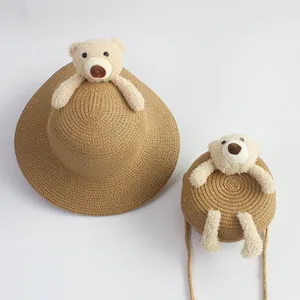 Detailed view of straw sun hat and matching small round bag with plush bear ornament