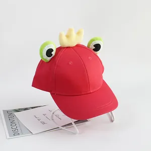 Détail d'une casquette enfant rouge avec yeux de grenouille et couronne en peluche