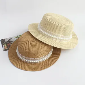 Gros plan de chapeaux de paille plats avec dentelle blanche et ornements de perles