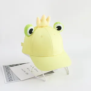 Détail d'une casquette en toile de coton jaune clair avec yeux de grenouille en peluche
