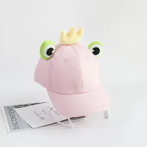 Détail d'une casquette rose pour enfant avec yeux de grenouille 3D et couronne en peluche