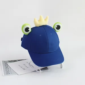 Détail d'une casquette grenouille bleu roi avec couronne jaune et grands yeux mignons