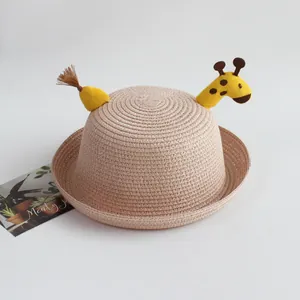 Detail of beige straw hat with cute yellow giraffe embroidery and brown tassel decoration