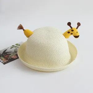 Detailed macro view of cream woven straw sun hat featuring a cute yellow giraffe topper