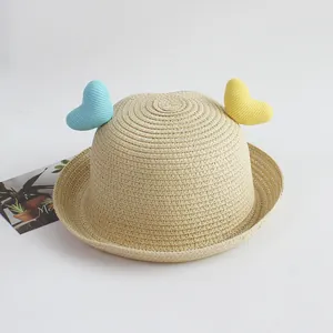 Detailed texture of beige straw sun hat featuring blue and yellow knitted heart accents