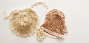 Flat lay of handmade straw hats for kids and adults with delicate white lace trim detail