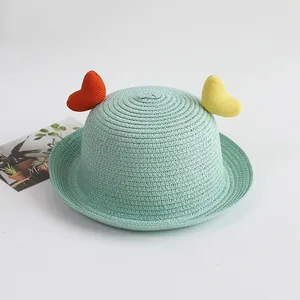 Close-up of mint green straw hat featuring colorful heart accents and fine woven texture
