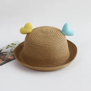 Detail of child straw hat with yellow and blue heart decorations and rolled brim design