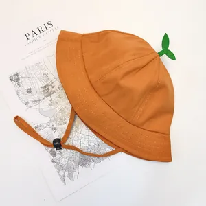 Detail of orange cotton baby bucket hat featuring a green sprout top and adjustable chin strap