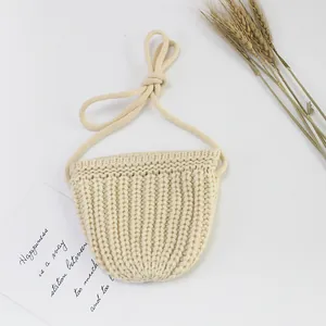 Makro-Detail der handgestrickten halbkreisförmigen Mini-Tasche aus cremeweißem Garn