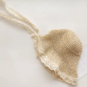 Détail d'un chapeau en paille tissé avec bordure en dentelle blanche et rubans réglables