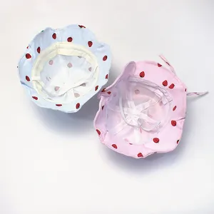 Detail view of light blue and pink strawberry cotton sun hats with adjustable wind ropes