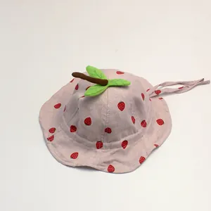 Detail of pink cotton baby sun hat with strawberry print and chin strap on white background