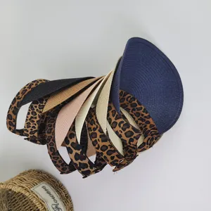 Detail view of woven straw sun visors in various colors with a decorative flower basket