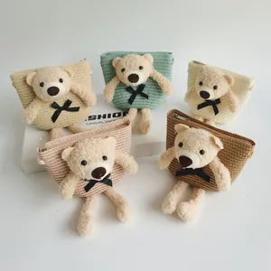 Detailed view of five colorful children's straw bags with cute plush teddy bear decor