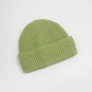 Gros plan d'un bonnet en maille vert clair avec texture côtelée et large bord replié
