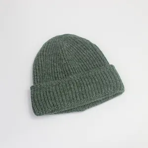 Détail de la texture en tricot côtelé vert foncé et du revers d'un bonnet d'hiver chaud