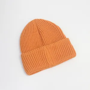 Gros plan détaillé du bonnet en maille côtelée orange montrant la texture épaisse