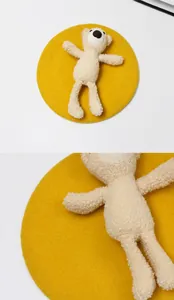 Detail of yellow wool beret featuring a 3D plush teddy bear and soft winter texture