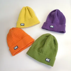 Detailed close-up showing thick ribbed texture and V.E. logo labels on colorful knit beanies