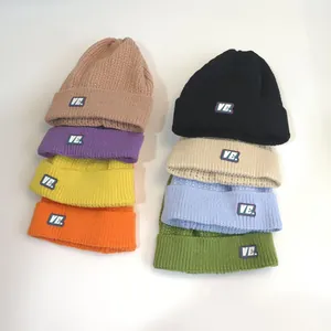 Detail view of eight colorful ribbed knit beanies with V.E. logo on a clean white background