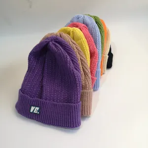 Detail showing various colors of ribbed knit beanies with thick texture and VE woven labels