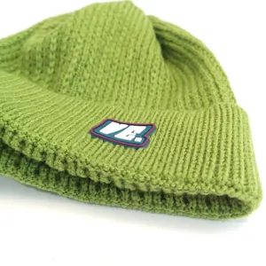 Detail of green chunky knit beanie showing the ribbed texture and VE. letter badge