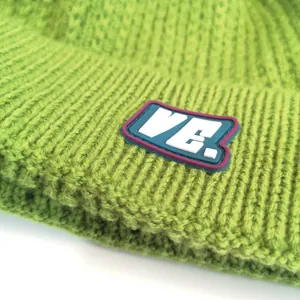 Grass green cable knit beanie with VE logo patch shown from a 45-degree angle closeup