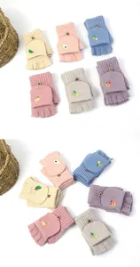 Detail of knitted flip-top gloves with fruit embroidery and wooden button closure