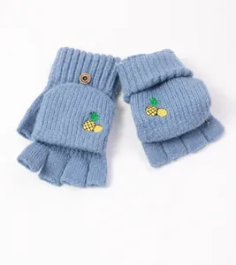 Close-up of blue knitted fingerless glove with pineapple embroidery and decorative button