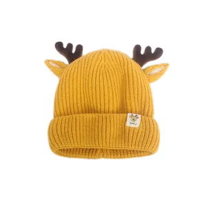 Gros plan du bonnet tricoté jaune pour bébé avec bois de renne en peluche et oreilles douces