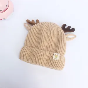 Détail d'un bonnet en tricot beige pour bébé avec bois de cerf marron et petites oreilles