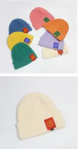 Details von gerippten Strickmützen mit lächelndem Cartoon-Aufnäher in verschiedenen Farben