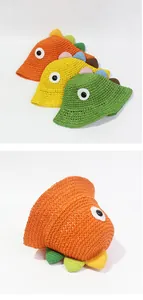 Detalle de sombreros de paja para niños con crestas de colores y ojos de dinosaurio 3D