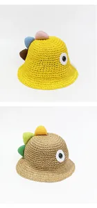 Detalle del tejido de paja y adornos de dinosaurio en sombreros de verano infantiles