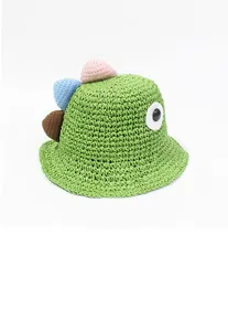 Detalle de sombrero de paja verde con ojo de dinosaurio y pinchos 3D de colores