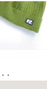 Dettaglio del berretto in maglia a trecce verde avocado con toppa e trama in lana morbida